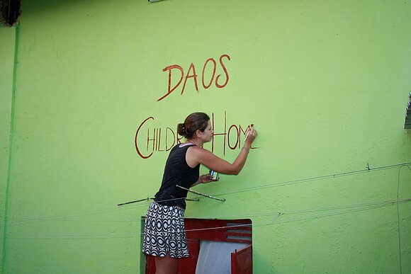 DAOS Projekt Kenia Mädchen mal Schriftzug auf Hauswand